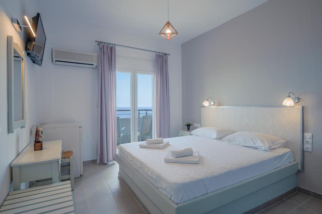 a white bedroom with a large bed and a window at Pantheon in Patitiri