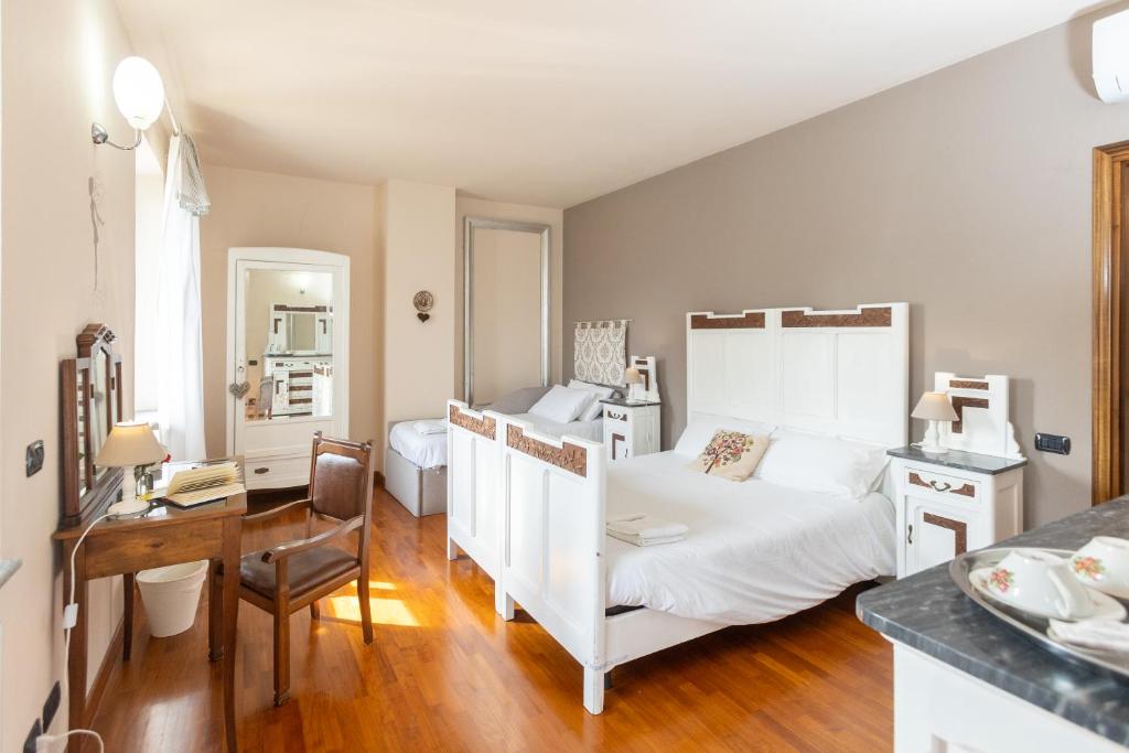a bedroom with a white bed and a desk and a kitchen at Lanterna delle Fate House and swimming pool for exclusive use in Asti