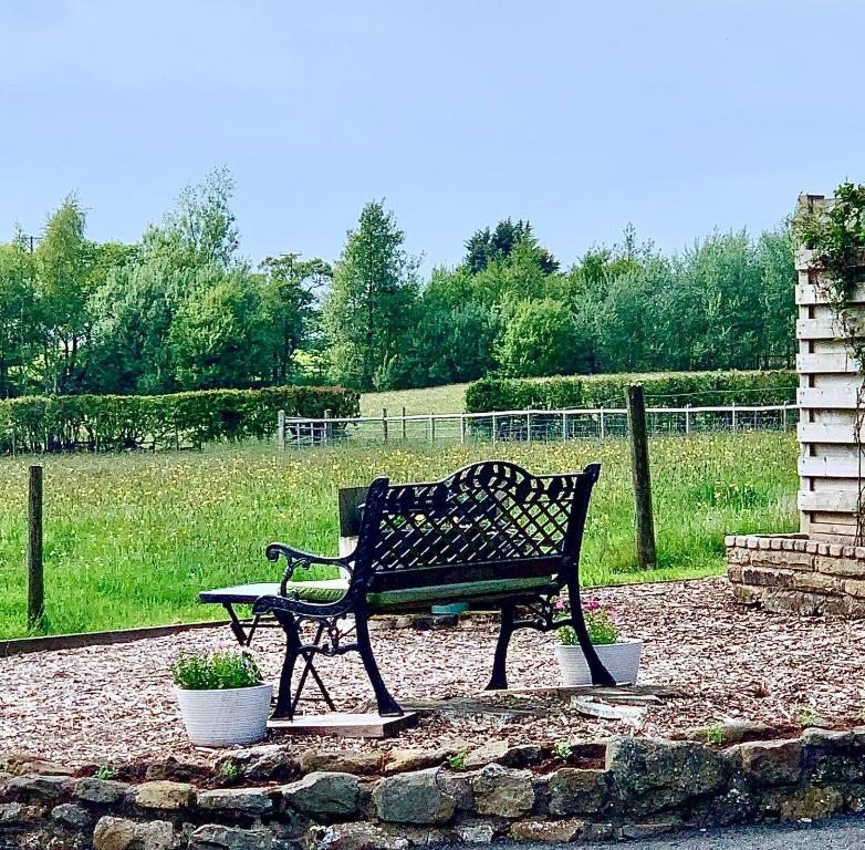 a park bench sitting next to a field at Sunset View a quiet and romantic rural retreat for 2 adults just outside ingleton in Ingleton 