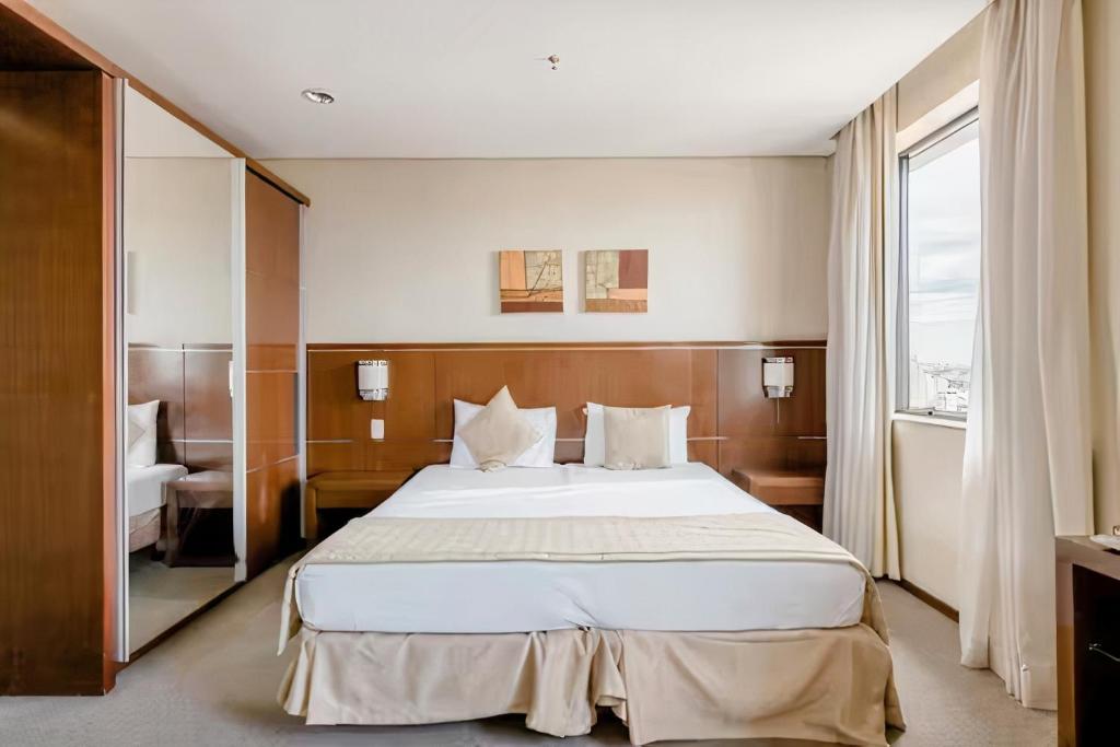 ein Hotelzimmer mit einem großen Bett und einem Fenster in der Unterkunft Flat Osasco Trade - Espaço confortável com internet rápida e piscina in Osasco