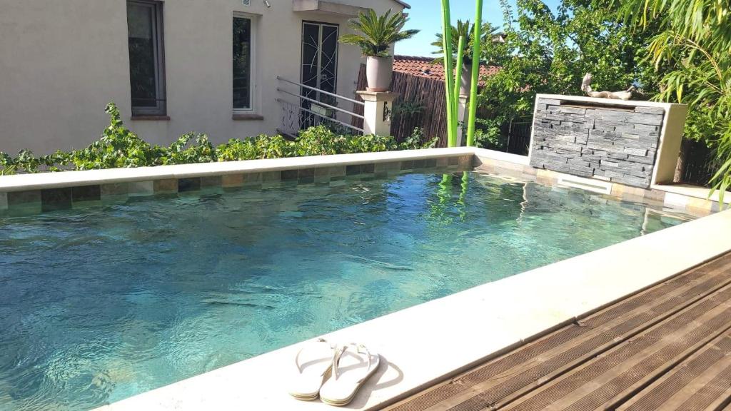 una piscina con un par de sandalias. en logement atypique avec jacuzzi et piscine en Carnoules