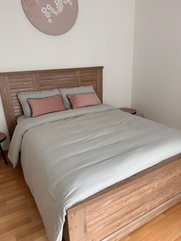 une chambre avec un grand lit avec des oreillers roses dans l'établissement Appartement 1 chambre rue Faubourg de Besançon, à Montbéliard