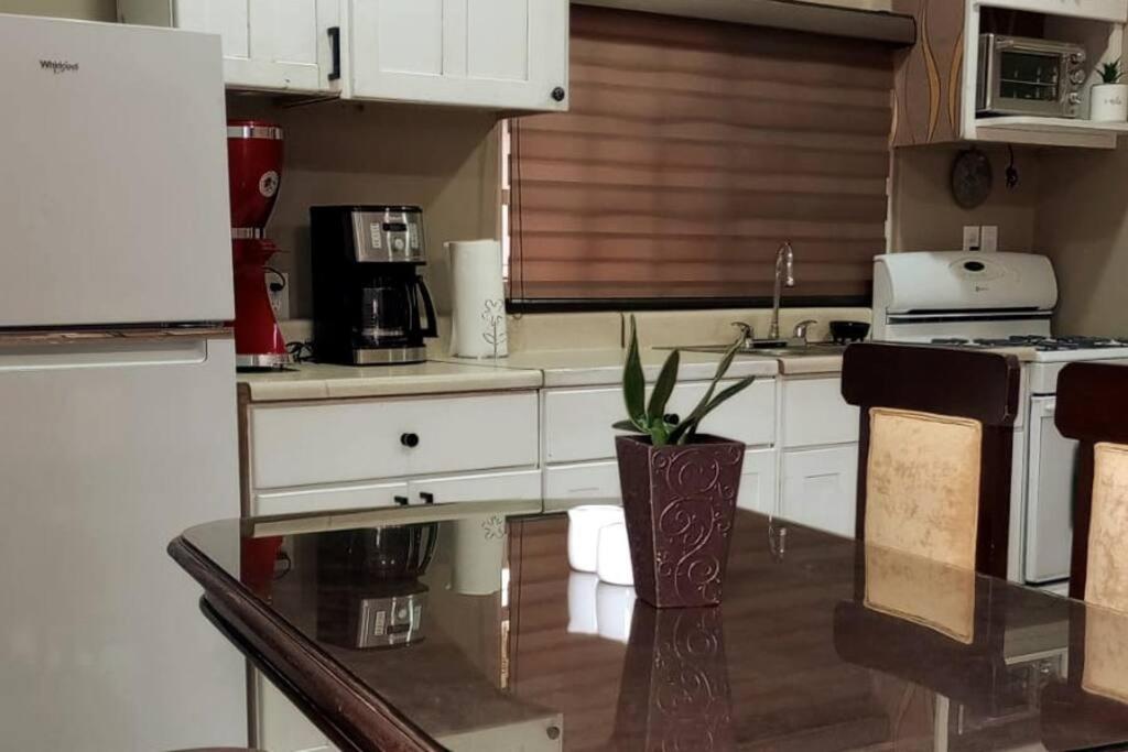 une cuisine avec des placards blancs et une table avec une plante en pot dans l'établissement Mini Studio Para Fines., à Rosarito