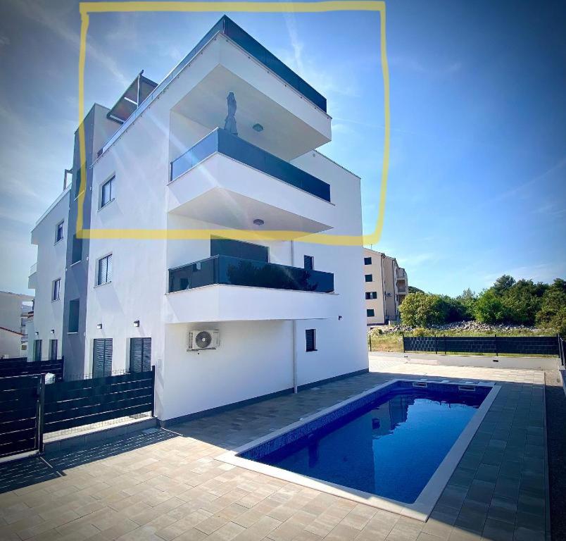 een gebouw met een zwembad ervoor bij Apartment Agnes with 63 m2 Rooftop Terrace, Grill and Pool in Okrug Gornji
