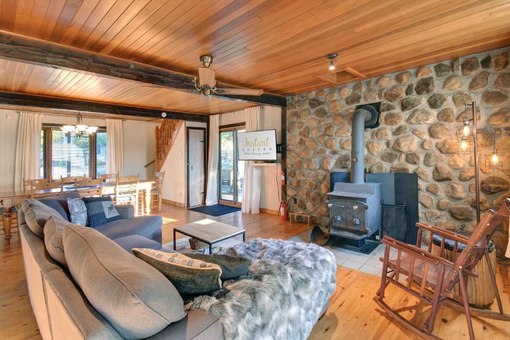 a living room with a couch and a stone fireplace at The Woodland Cabin by Instant Suites - Old Village Mont-Tremblant in Mont-Tremblant