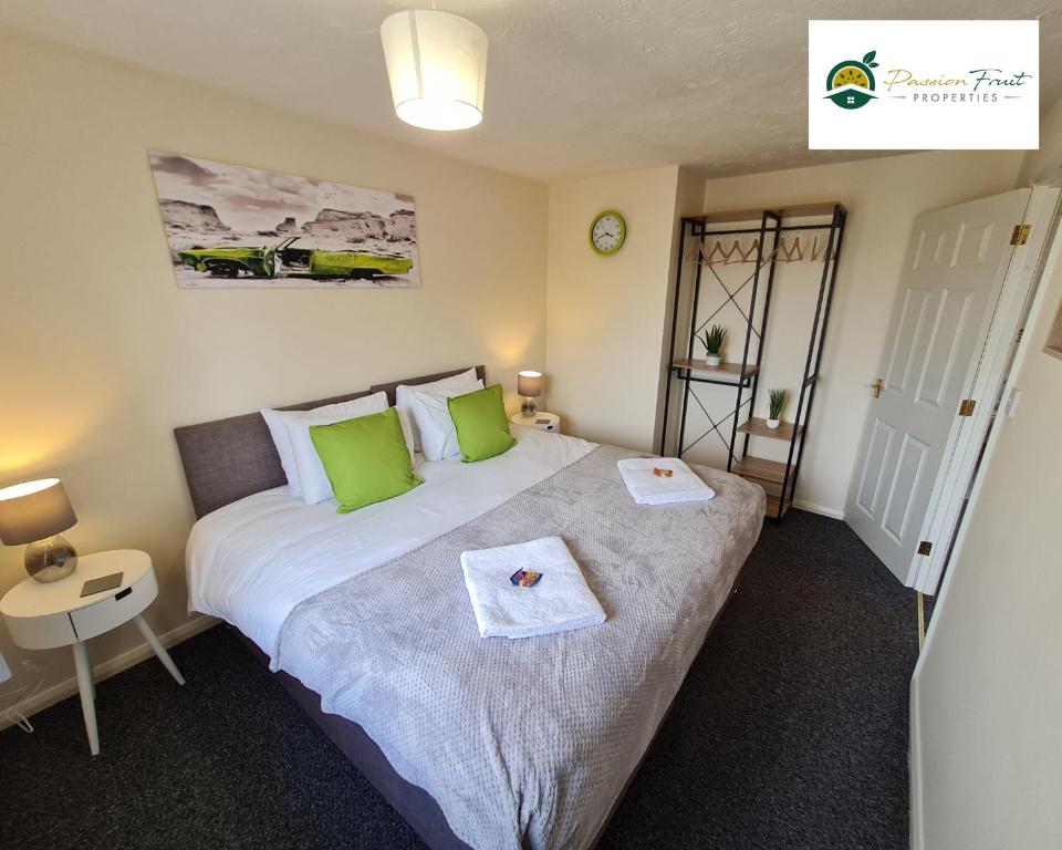 a bedroom with a large bed with green pillows at 3 Bedroom House at Low rate- near Coventry City Centre with Wi-fi Netflix Unlimited, driveway parking by Passion Fruit Properties- 16RWC in Coventry