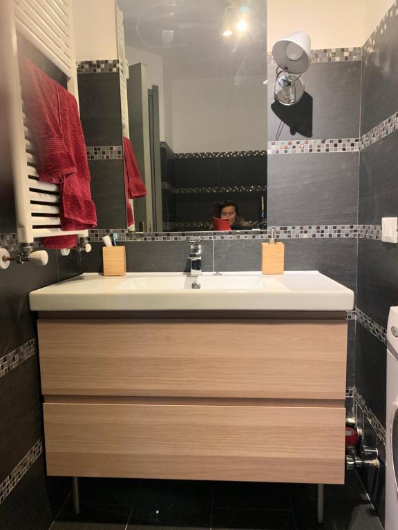 een badkamer met een wastafel en een persoon in een spiegel bij giomein, appartamento di charme artistico ,CIR 0279 in Breuil-Cervinia