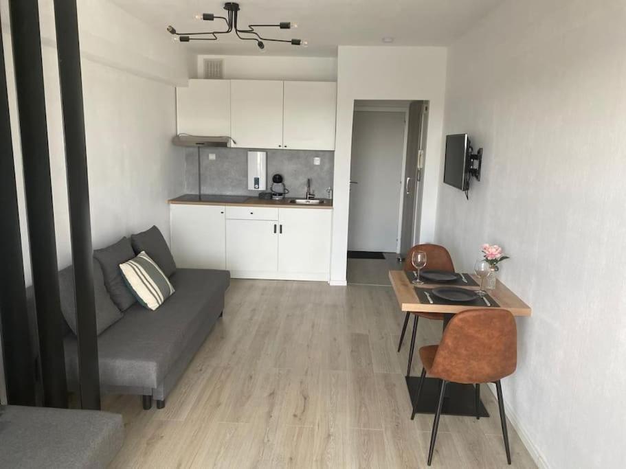ein Wohnzimmer mit einem Sofa und einem Tisch sowie eine Küche in der Unterkunft Nieuwe studio Westende Edelweiss in Middelkerke
