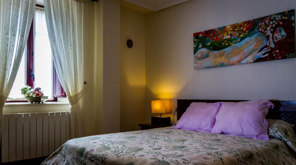 1 dormitorio con 1 cama con una pintura en la pared en Casa Zabalena, en Górliz-Elexalde