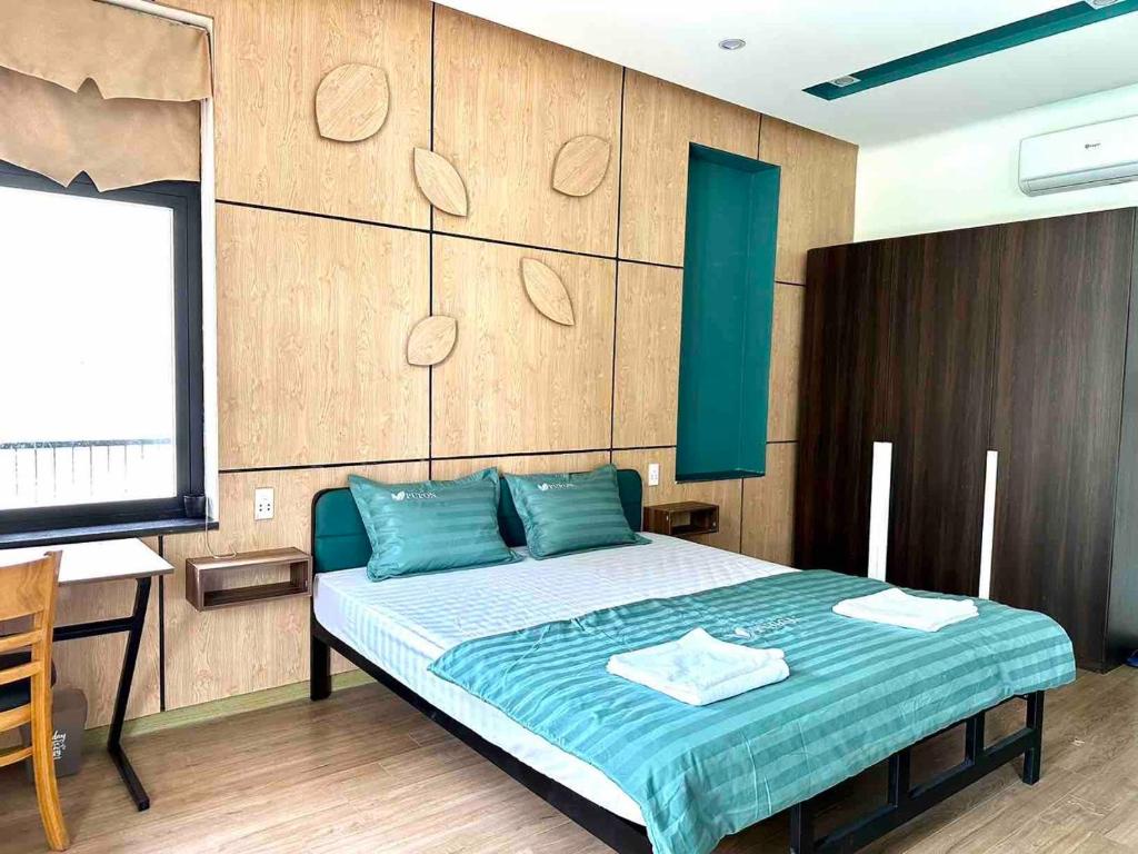 sypialnia z łóżkiem z niebieską pościelą i biurkiem w obiekcie PUPON Homestay and Coffee w mieście Quang Ngai