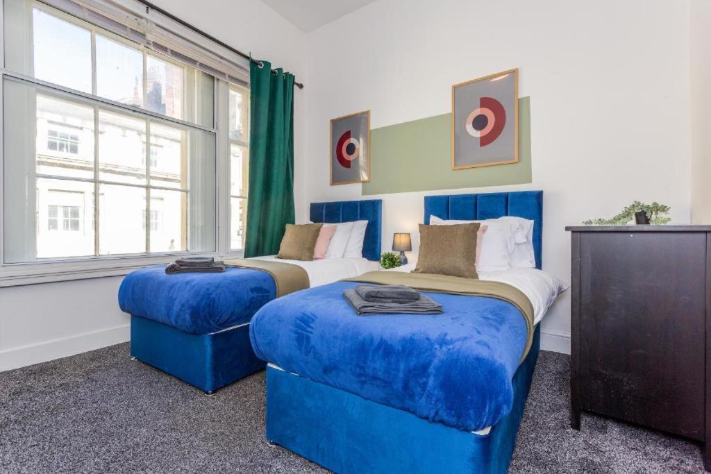 a bedroom with two beds with blue ottomans at Newcastle's Most Central Apartment - Sleeps 10 in Newcastle upon Tyne