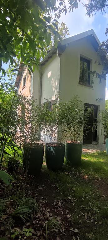 une maison avec trois grands pots devant elle dans l'établissement Le petit Ermitage, à Méré