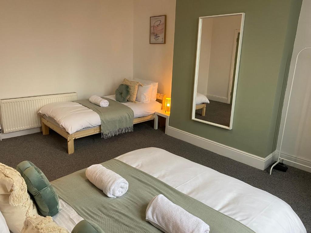 ein Zimmer mit zwei Betten und einem Spiegel in der Unterkunft Overhill 3 bedroom flat 5 beds, free parking, ideal for Contractors in Gateshead