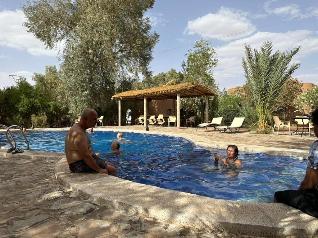 un grupo de personas sentadas en una piscina en Relais Hamada Du Draa, en Mhamid