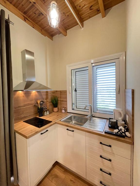 a kitchen with white cabinets and a sink and two windows at Vila Arial in Vlorë