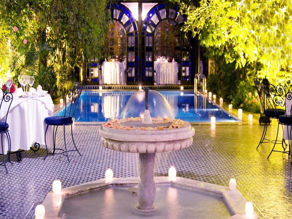 una fuente frente a una piscina con mesas y sillas en Palais Shéhérazade & Spa, en Fez