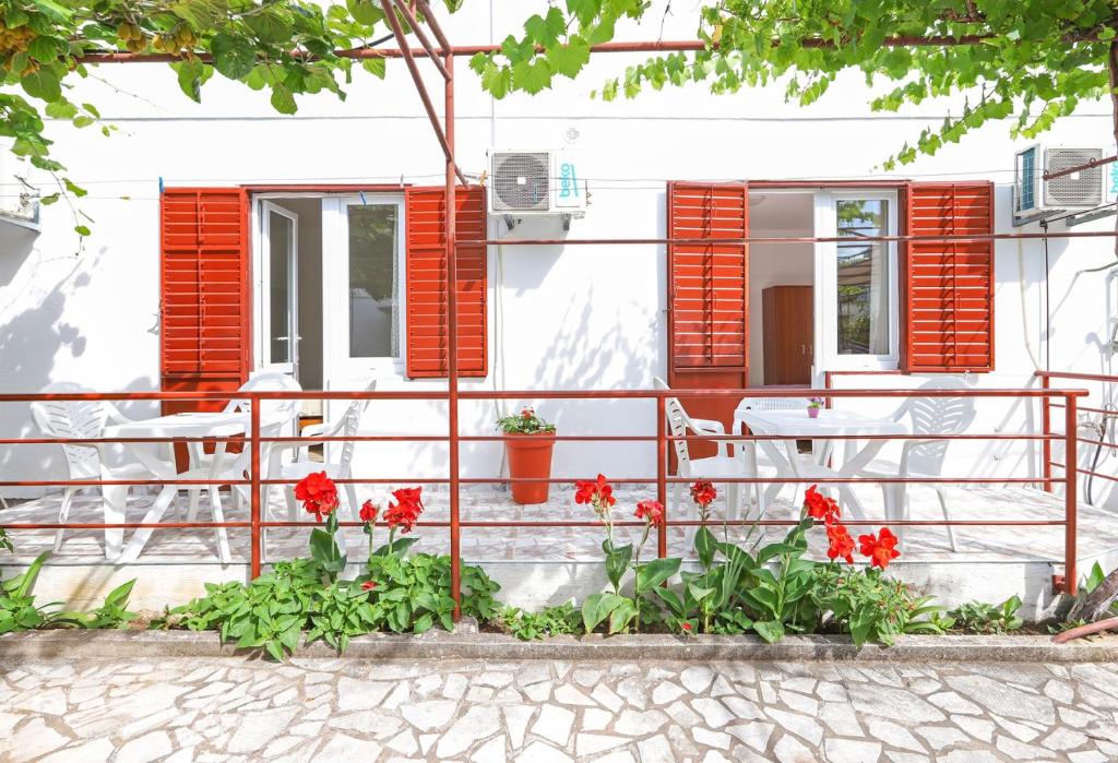 una casa con persianas rojas y flores delante de ella en Apartmani i sobe Radojičić, en Bijela