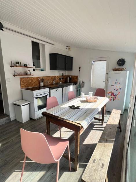 a kitchen with a table and pink chairs in a room at La maison du Mauret in Andernos-les-Bains