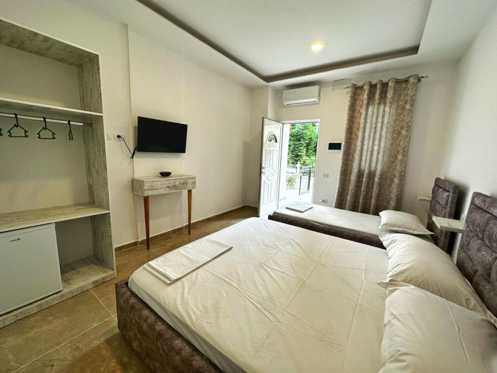 - une chambre avec un grand lit blanc et une télévision dans l'établissement Oasis The Villa, à Durrës