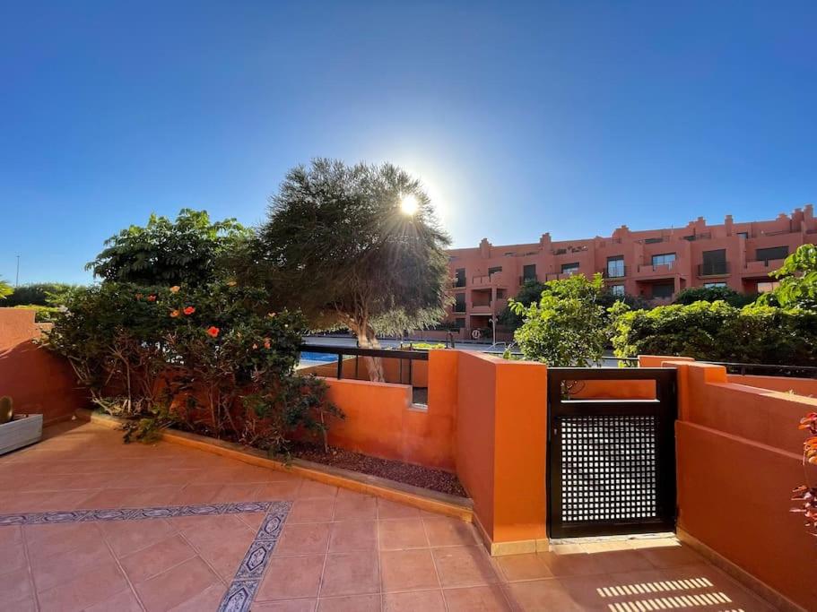Cozy apartment with large terrace next to the pool في La Tejita: بلكونه لها سور برتقالي واشجار ومبنى