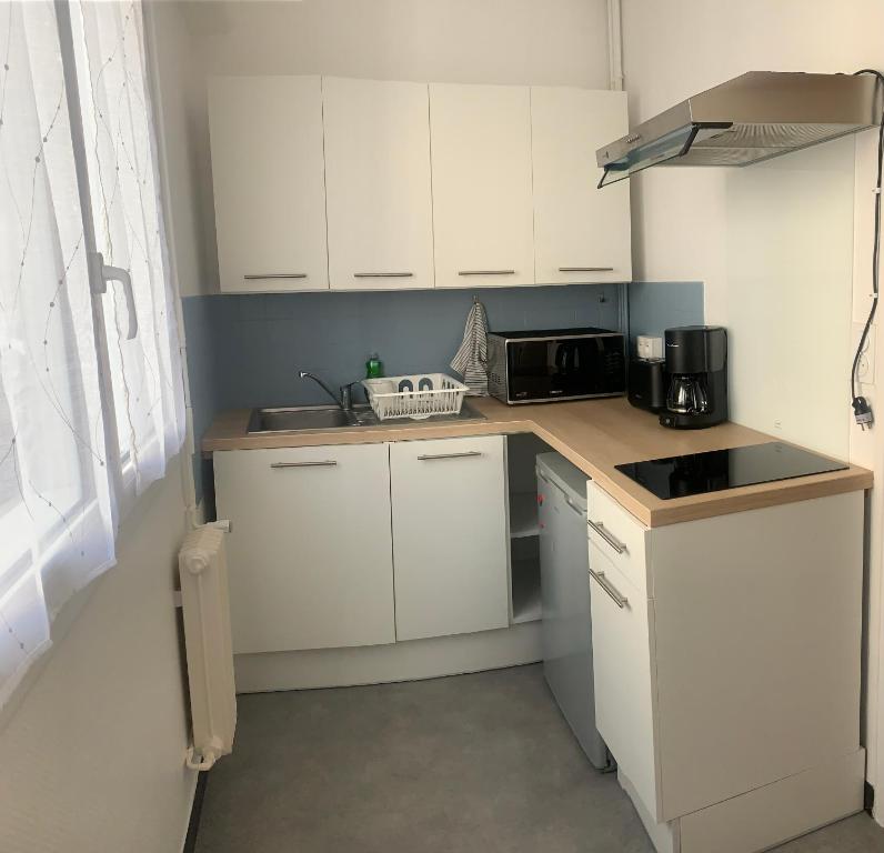 une petite cuisine avec des armoires blanches et un micro-ondes dans l'établissement Location 2 pers centre historique de quimper, à Quimper