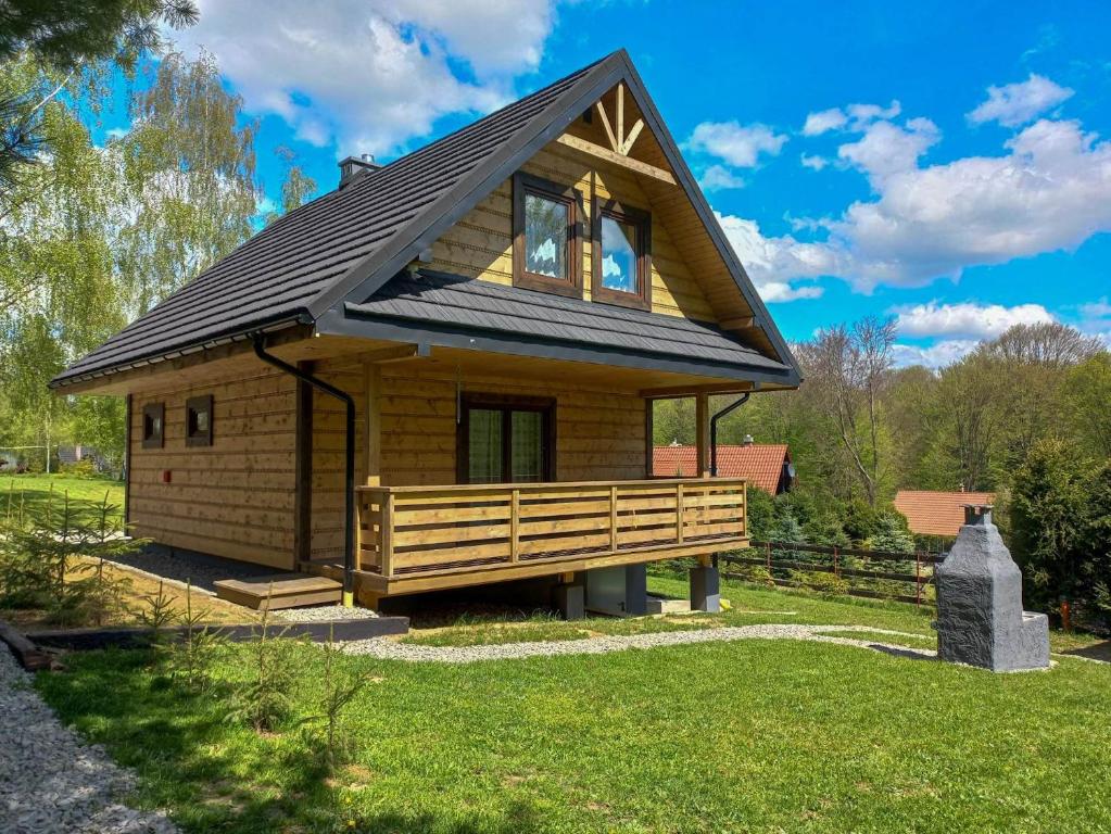 una piccola casa in legno con tetto nero di Chata Tołhaja a Polańczyk