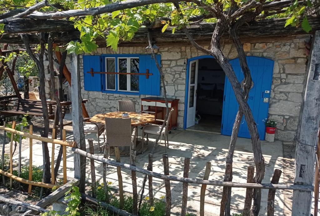 ein Haus mit einer blauen Tür sowie einem Tisch und Stühlen in der Unterkunft Casa Delle Olive in Mošćenička Draga