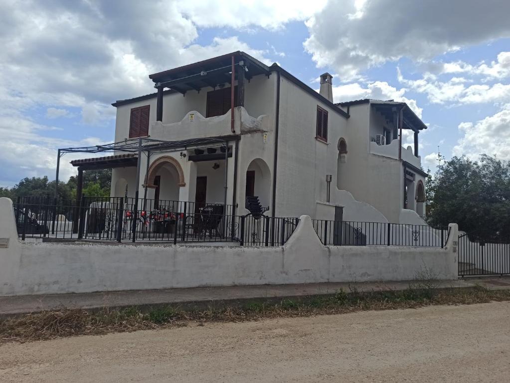 een wit huis met een hek ervoor bij sa janna in Orosei