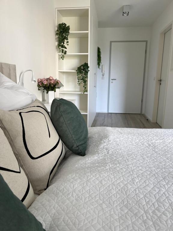 ein Schlafzimmer mit einem großen weißen Bett mit grünen Kissen in der Unterkunft Wanderlust Petrisberg - Studio 54 in Trier