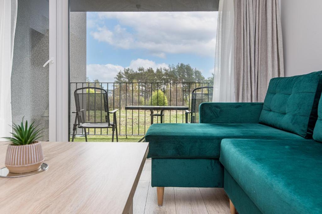 a living room with a green couch and a balcony at Jūros banga in Palanga