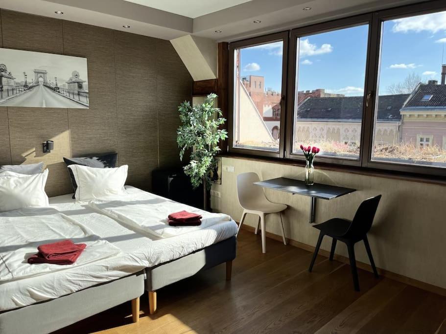 1 dormitorio con cama, mesa y ventanas en Bright/sunny/apartment w/shared rooftop terrace 360 view, en Budapest