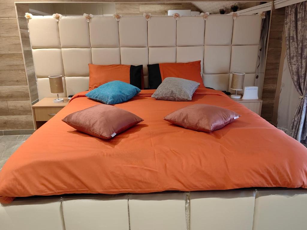 a large orange bed with three pillows on it at Spa Apartman OGLEDALO in Zaječar