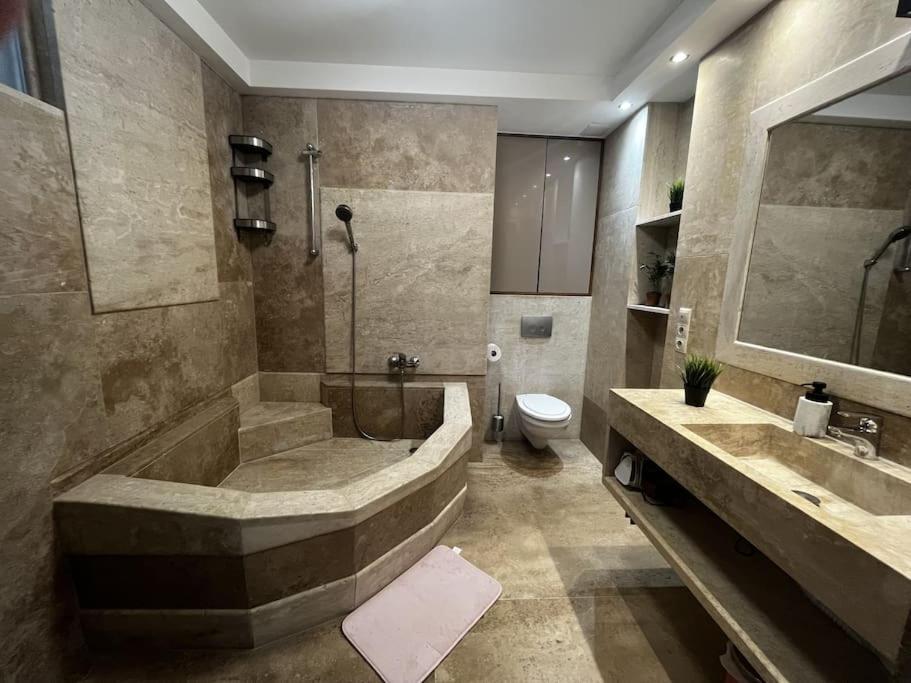 a bathroom with a tub and a toilet and a sink at Sunny/stylish rooftop home/private balcony shared jacuzzi in Budapest