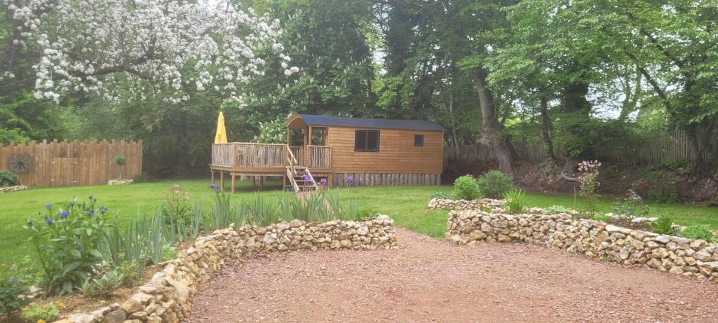 une petite cabane en bois dans une cour avec un jardin dans l'établissement Roulotte Escapade nature à Morainville - Normandie, à Morainville-près-Lieurey