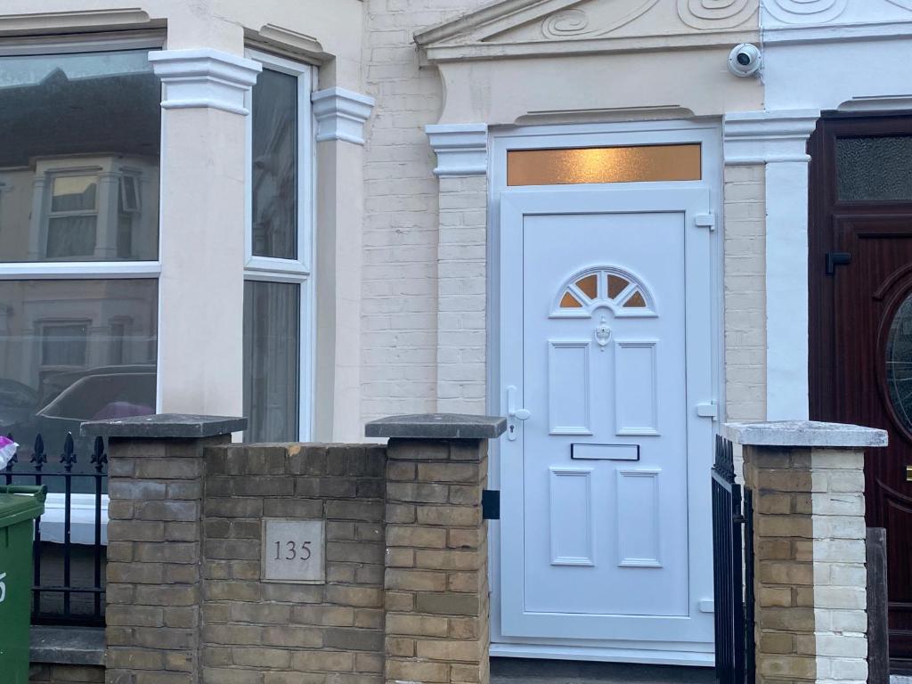 uma porta branca numa casa com uma janela em Cosy house in Newham em Londres