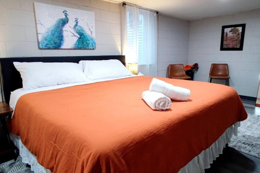 um quarto com uma grande cama laranja com duas toalhas em Spacious Suite Close to Downtown Indy/ King Bed em Indianápolis