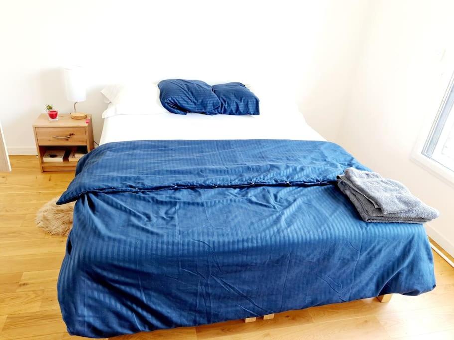 - un lit avec une couverture bleue dans l'établissement Appartement lumineux Gagny - Paris banlieue, à Gagny