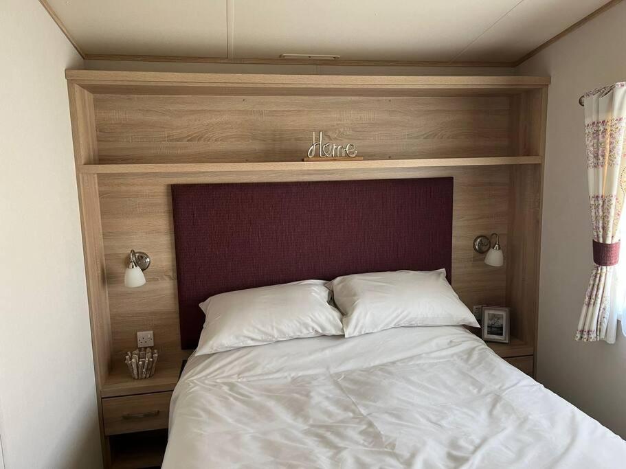 a bed with a wooden headboard in a bedroom at New Forest Retreat on a 5* Holiday Resort in New Milton