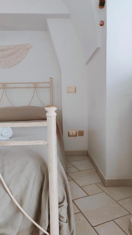 a white bed in a room with a tiled floor at Nonno Pasquale house in Locorotondo