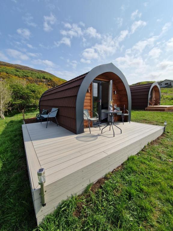 a circular house with a wooden deck in a field at Tighlochan pods in Scourie