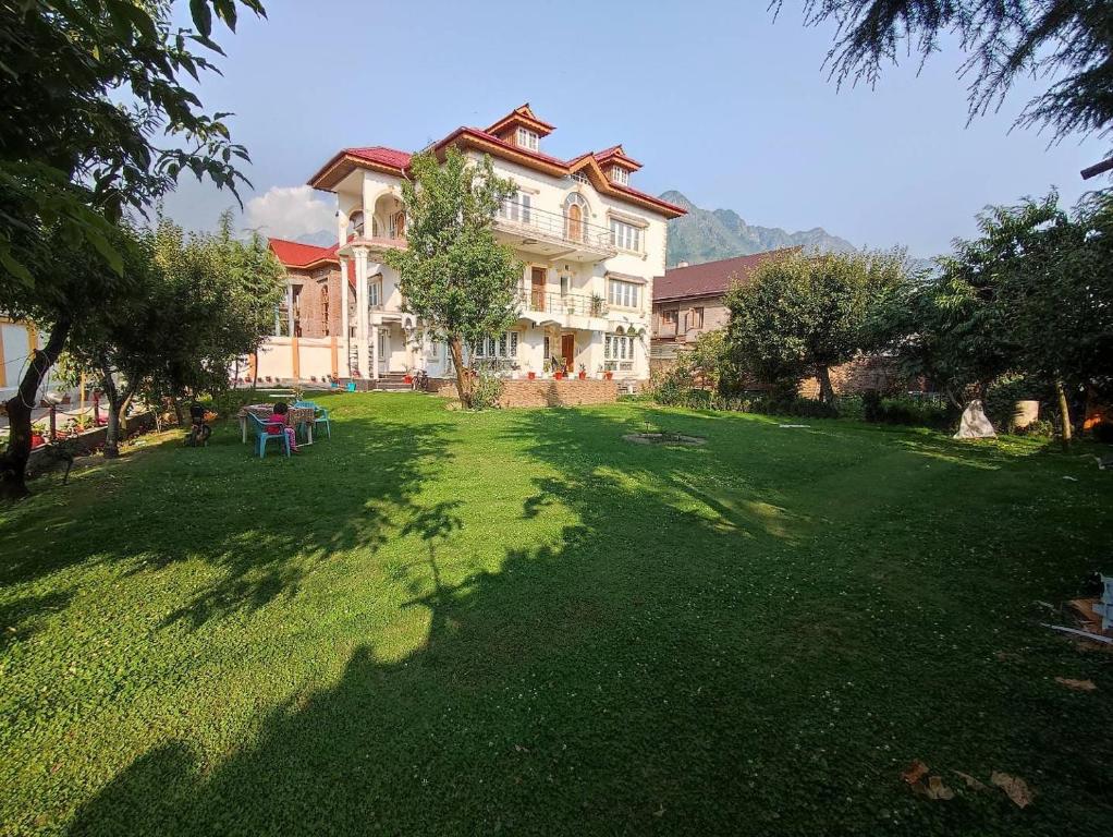 uma casa grande com um relvado verde em frente em THE CLOVER Home Stay em Srinagar