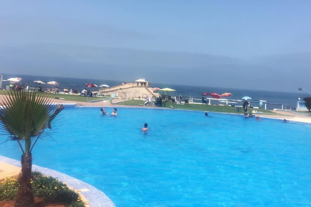 - une grande piscine avec des personnes à l'eau dans l'établissement Appartement avec magnifique piscine face à la mer, à Minaret de Mansuria