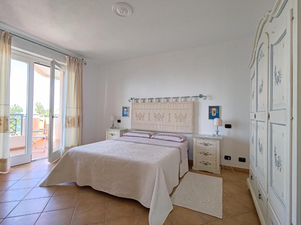 a white bedroom with a bed and a large window at Splendida vista sul mare in Nebida