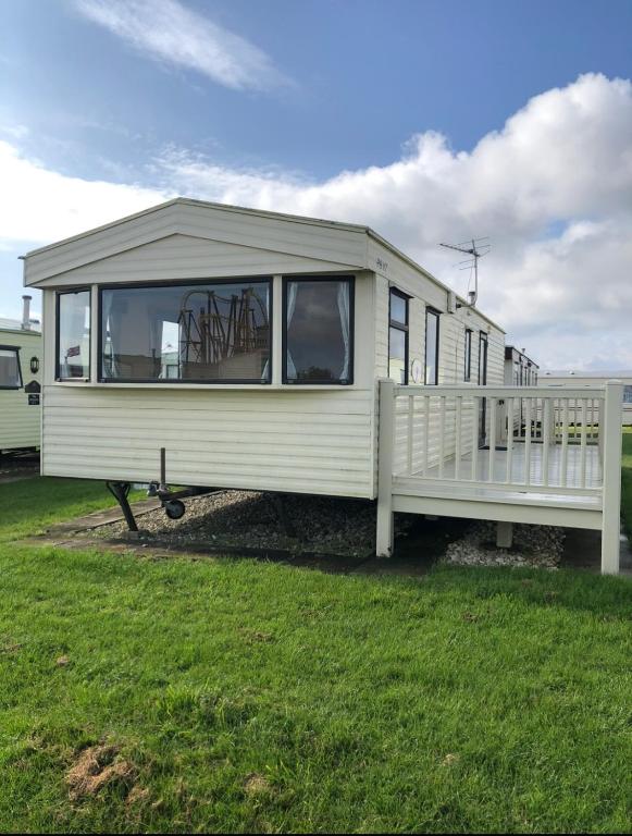 a white trailer with a porch on a grass field at Skegness - Ingoldmells Caravan Hire in Ingoldmells