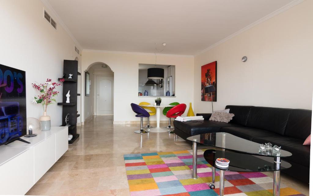 sala de estar con sofá negro y alfombra colorida en Luxe appartement Las Palmeras Calahonda, en Sitio de Calahonda