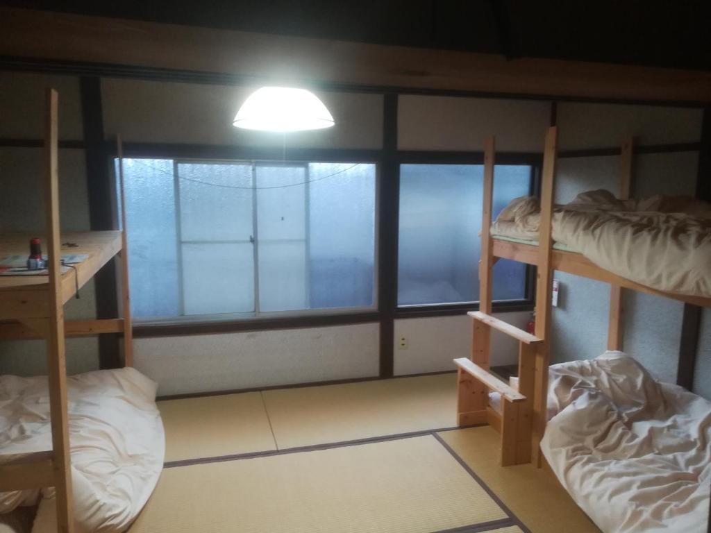 a room with three bunk beds and a window at ez guest house in Kyoto