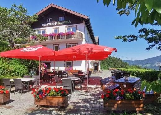 ein Restaurant mit Tischen und Sonnenschirmen vor einem Gebäude in der Unterkunft Alpengasthof Fernblick in Mönichkirchen