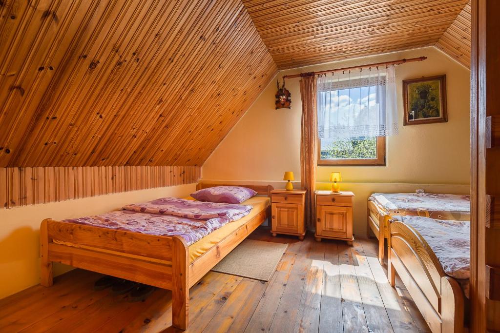 a bedroom with two beds in a room with wooden ceilings at Domek Bogdanka in Polańczyk