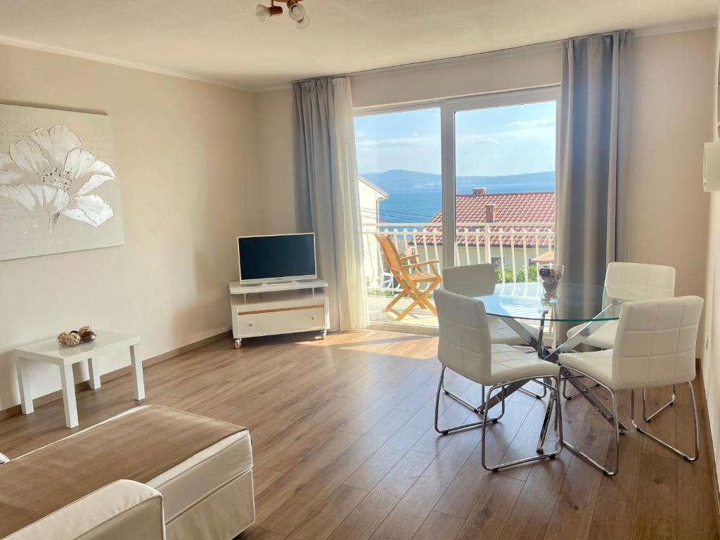 a living room with a table and chairs and a television at Apartment Araucaria in Crikvenica