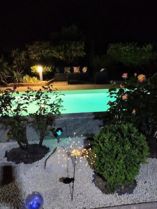 une piscine la nuit avec des arbres et des lumières dans l'établissement jolie Mazet avec piscine privée !, à Nîmes